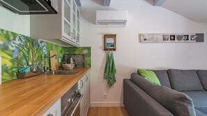 Cocina compacta con encimera de madera, horno empotrado y aire acondicionado de pared.
