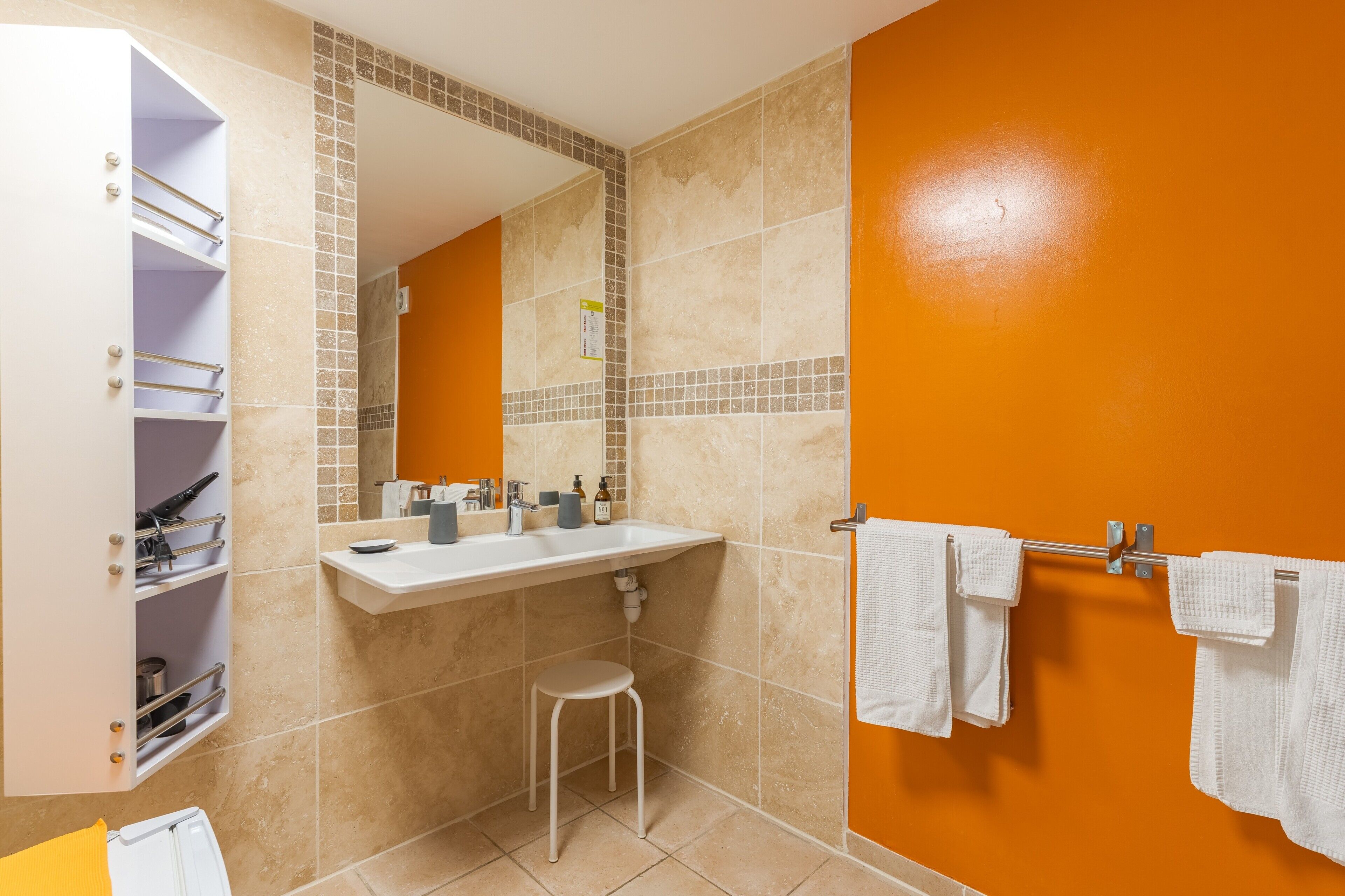 A bathroom with a white vanity, a sink, a mirror, and a towel rack.