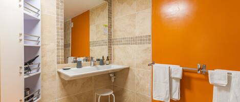 A bathroom with a white vanity, a sink, a mirror, and a towel rack.