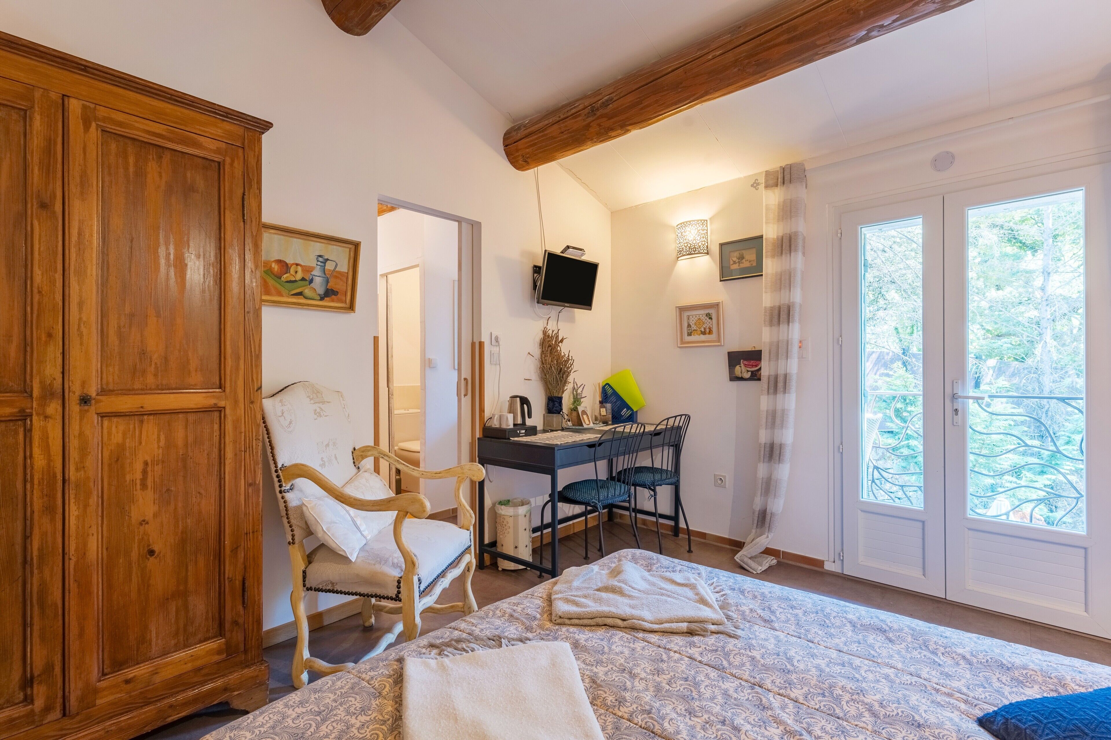 Una camera da letto con un letto, un armadio in legno, una scrivania, sedie e un televisore.