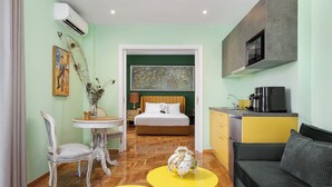 Habitación de hotel con cama, mesa de comedor, sofá y cocina equipada con microondas.