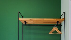 Un estante de madera de dos niveles, con una toalla blanca en cada uno, frente a una pared verde.
