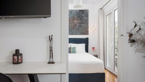 A modern bedroom with a bed, a desk, and a large window. - Hera Family Apartment, Olympian Zeus Apartments (Athens)