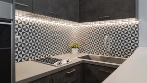 A modern kitchen with a geometric backsplash, a built-in stove, and a sink. - Zeus Grand Apartment, Olympian Zeus Apartments (Athens)