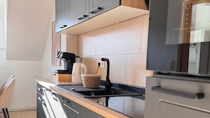 Une cuisine moderne avec des meubles gris, un plan de travail en bois et un four encastré.