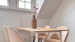 Un coin repas comprenant une table en bois, quatre chaises, un vase en osier orné de fleurs et un tapis en peau de vache.