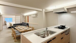 A modern kitchen with a central island, built-in cabinets, and a dining area with a low table and chairs. - bHotel Miyajima Omotesando 21 (Hatsukaichi)