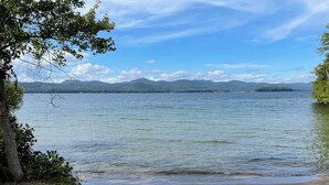 A lake with a clear view of distant mountains and a sandy shore.