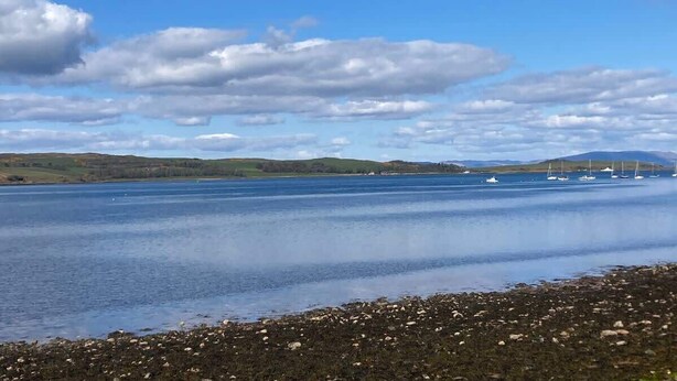 A calm lake with boats, a rocky shoreline, and distant hills under a partly cloudy sky. - The Waterside Apartment, ideal for families (Largs)