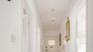 A hallway with white walls, a carpeted floor, and a door at the end. - The Waterside Apartment, ideal for families (Largs)