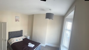 Une chambre à coucher avec un lit, une table de chevet et un luminaire suspendu.