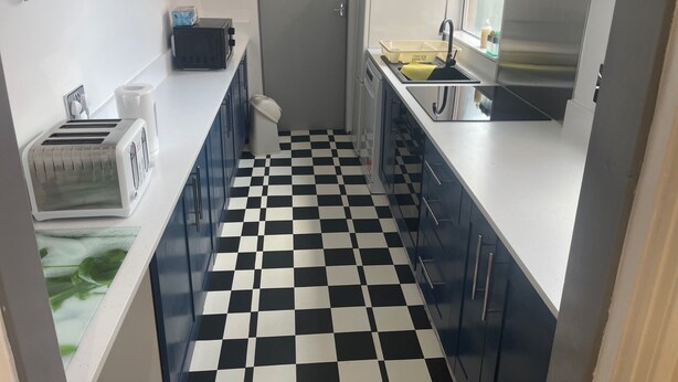 Une cuisine de taille réduite avec un sol à carreaux noirs et blancs, un grille-pain, un four à micro-ondes et un évier.