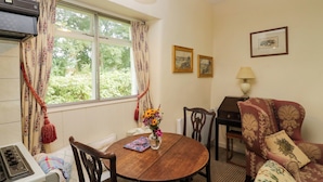 Una habitación acogedora con una mesa de comedor, sillas, un sofá, una lámpara y una ventana con cortinas.