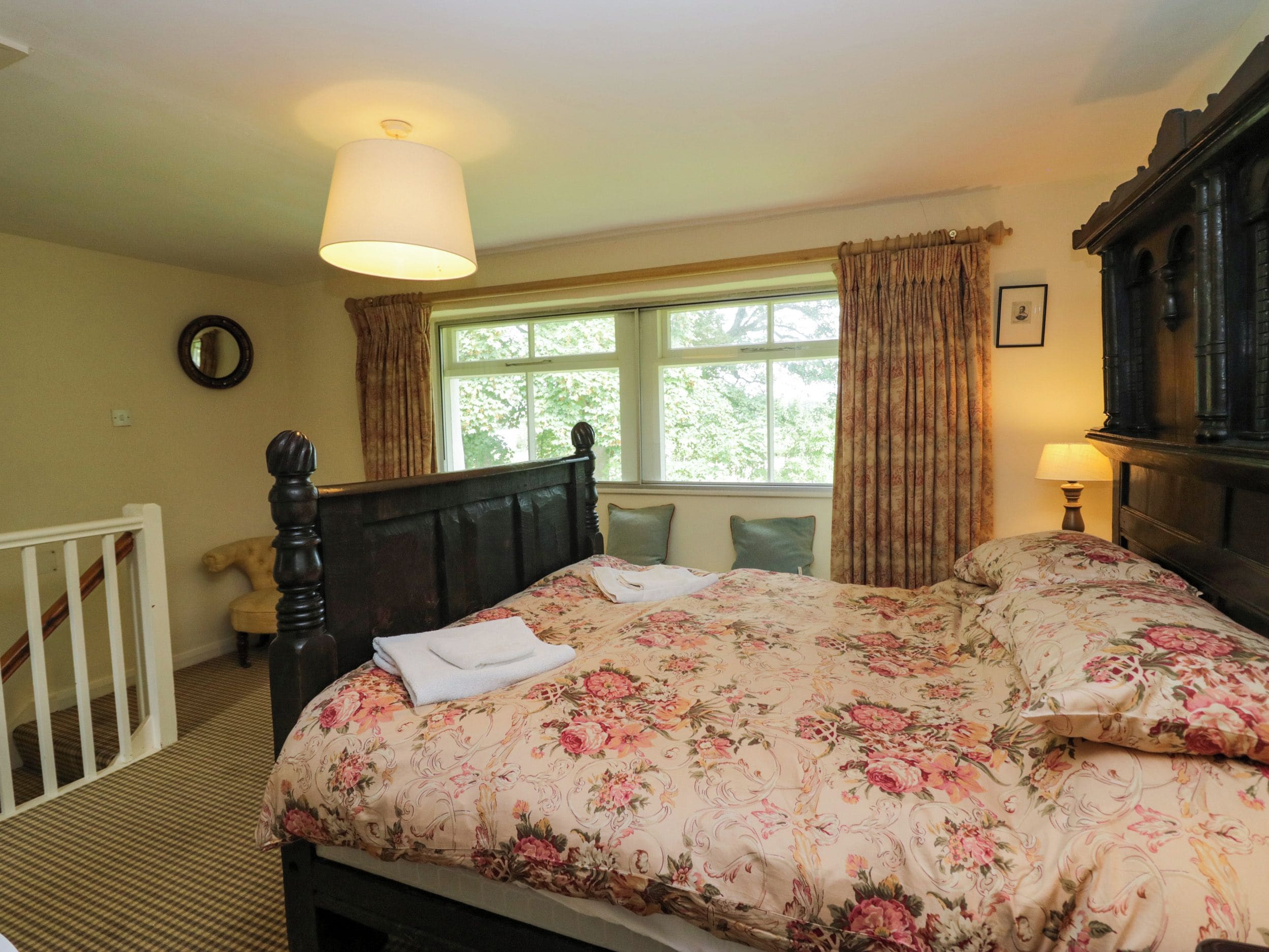 Quarto com cama, janela com cortinas, luminária de cabeceira e cabeceira de madeira.