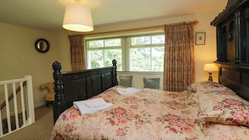 Quarto com cama, janela com cortinas, luminária de cabeceira e cabeceira de madeira.