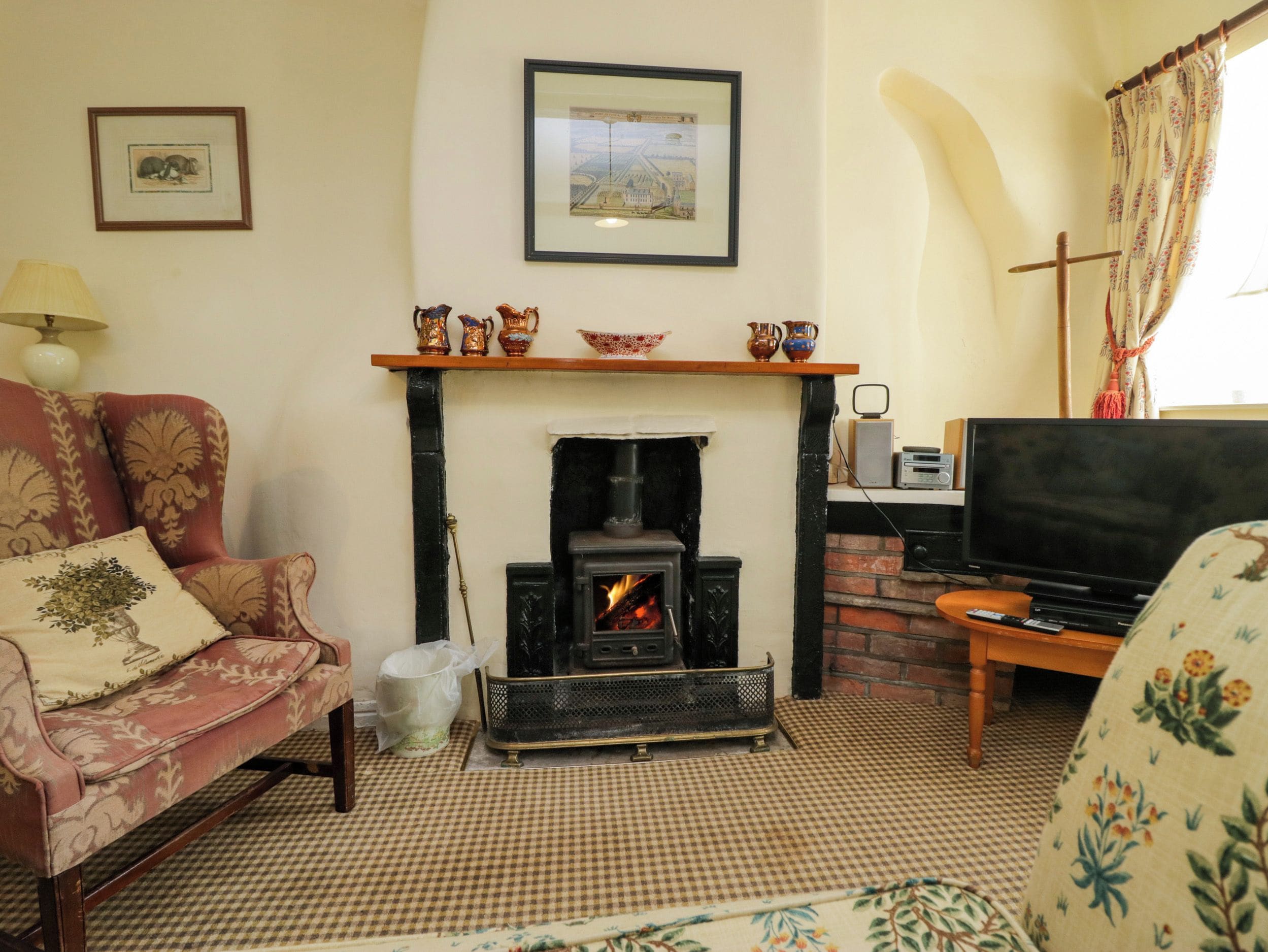 A living room with a fireplace, a sofa, a television, and a decorative shelf.