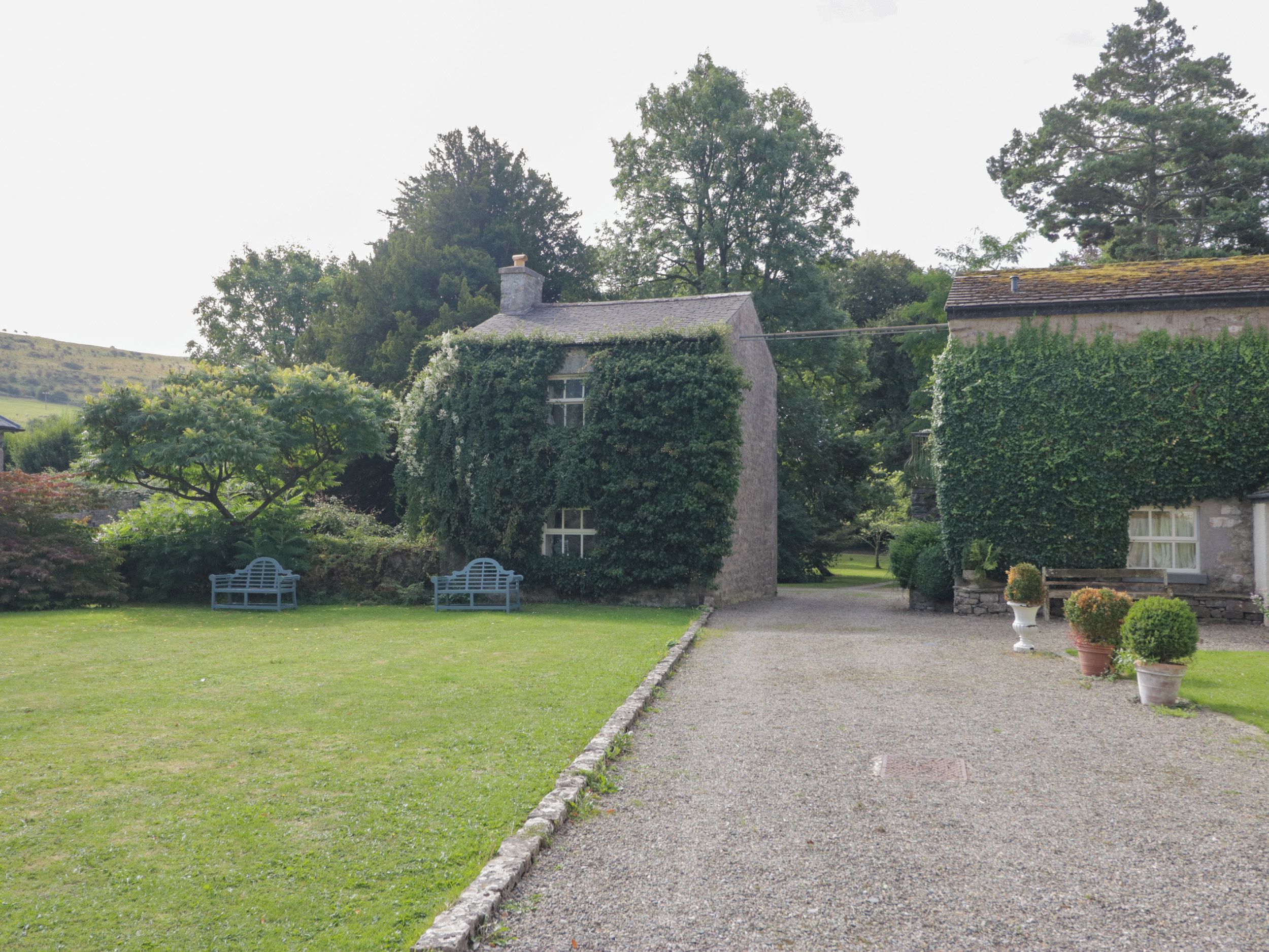 A house with a gravel driveway, a bench, and potted plants.