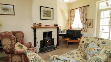 Una sala de estar con chimenea, un sofá, un televisor y una ventana con cortinas.