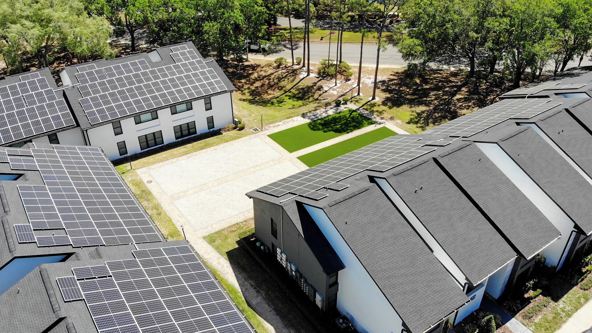 Een gebouw met meerdere daken voorzien van zonnepanelen en een parkeerplaats.
