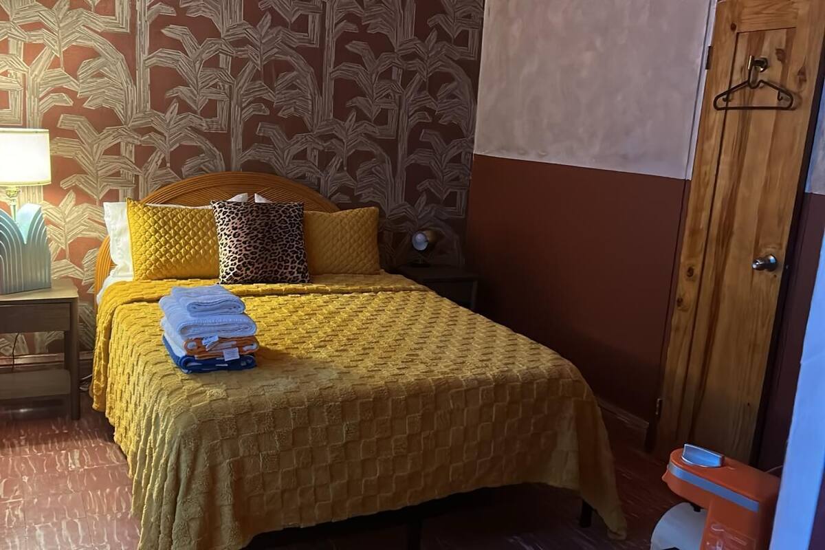 A room with a bed, a nightstand, a lamp, and a wooden door.