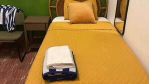 Una habitación con una cama, una mesita de noche, una silla y un espejo.