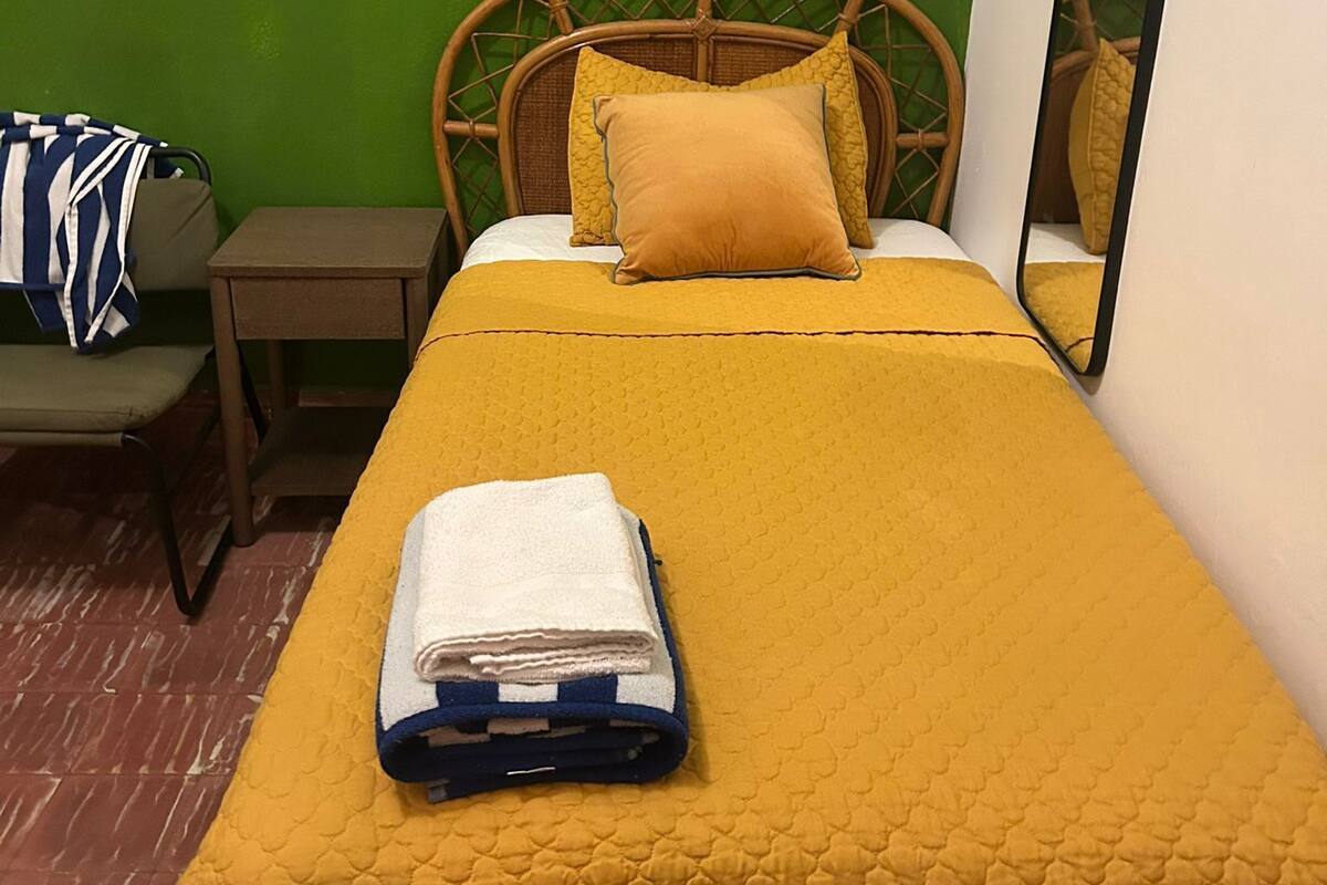 A room with a bed, a nightstand, a chair, and a mirror.