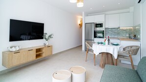 Uma cozinha moderna com armários brancos, forno embutido e uma área de refeições com mesa e cadeiras.
