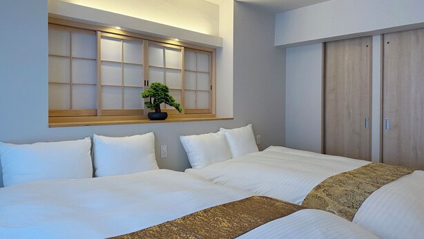 Habitación de hotel con dos camas, un ventanal con vistas y un armario de madera.