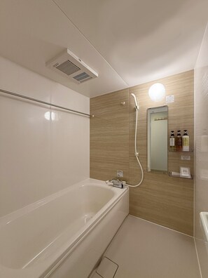 Un baño moderno con bañera, ducha y tocador con espejo.