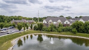 A residential area with houses, a pond, and a parking lot. - Top Floor Water View King Bed Pool Gym (Westerville)