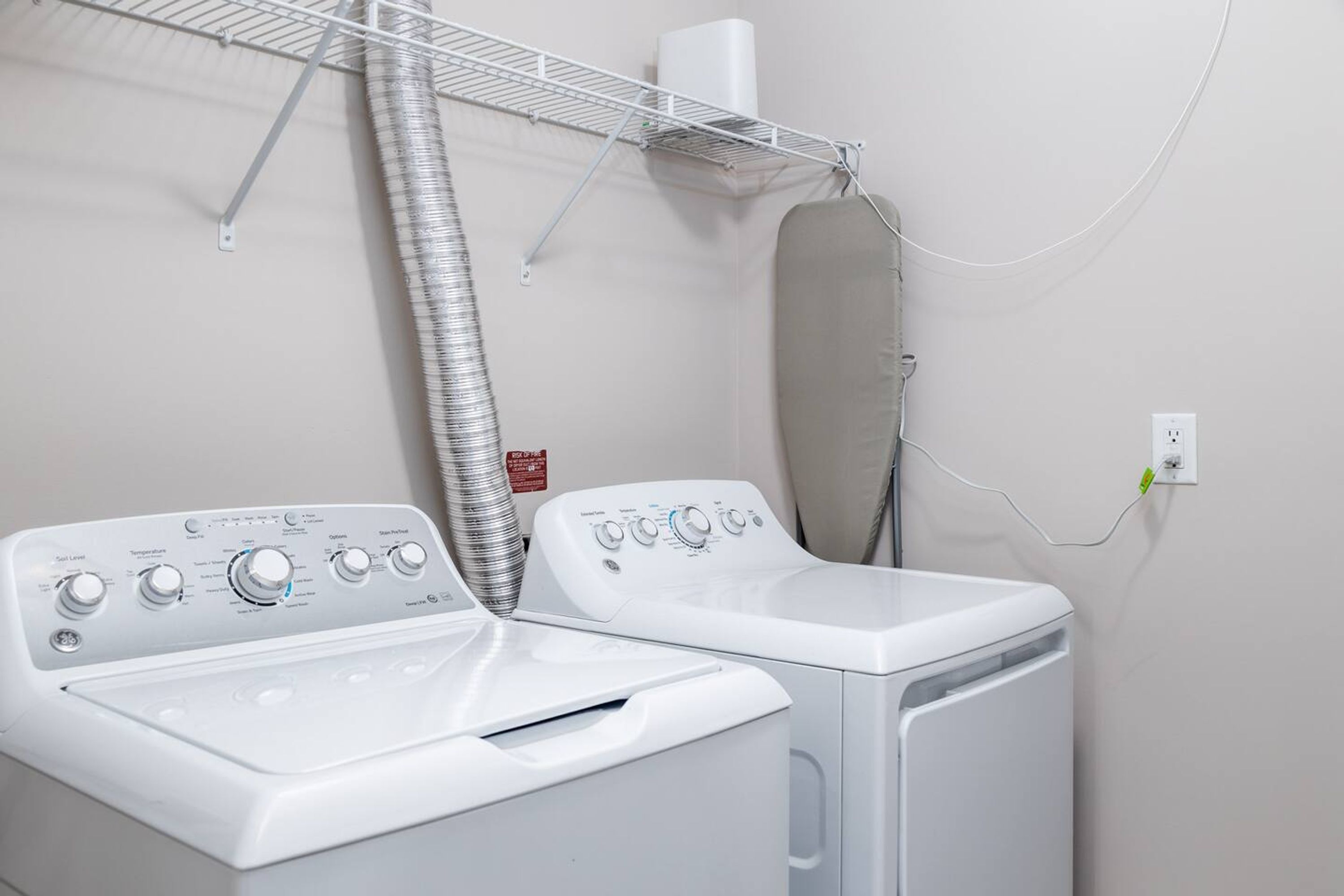 A laundry room with two front-loading washing machines and a drying rack.