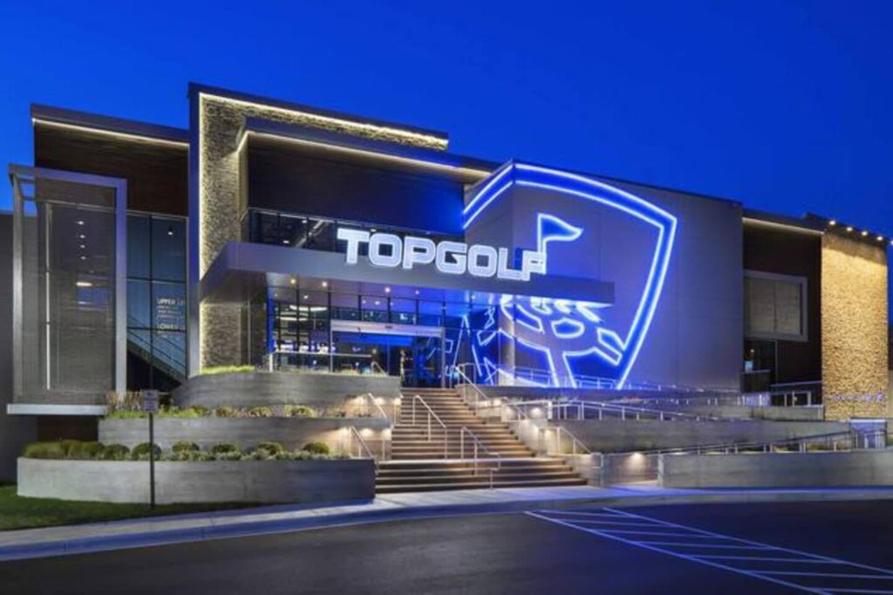 Un edificio moderno con un gran letrero iluminado que dice "TOPGOLF".