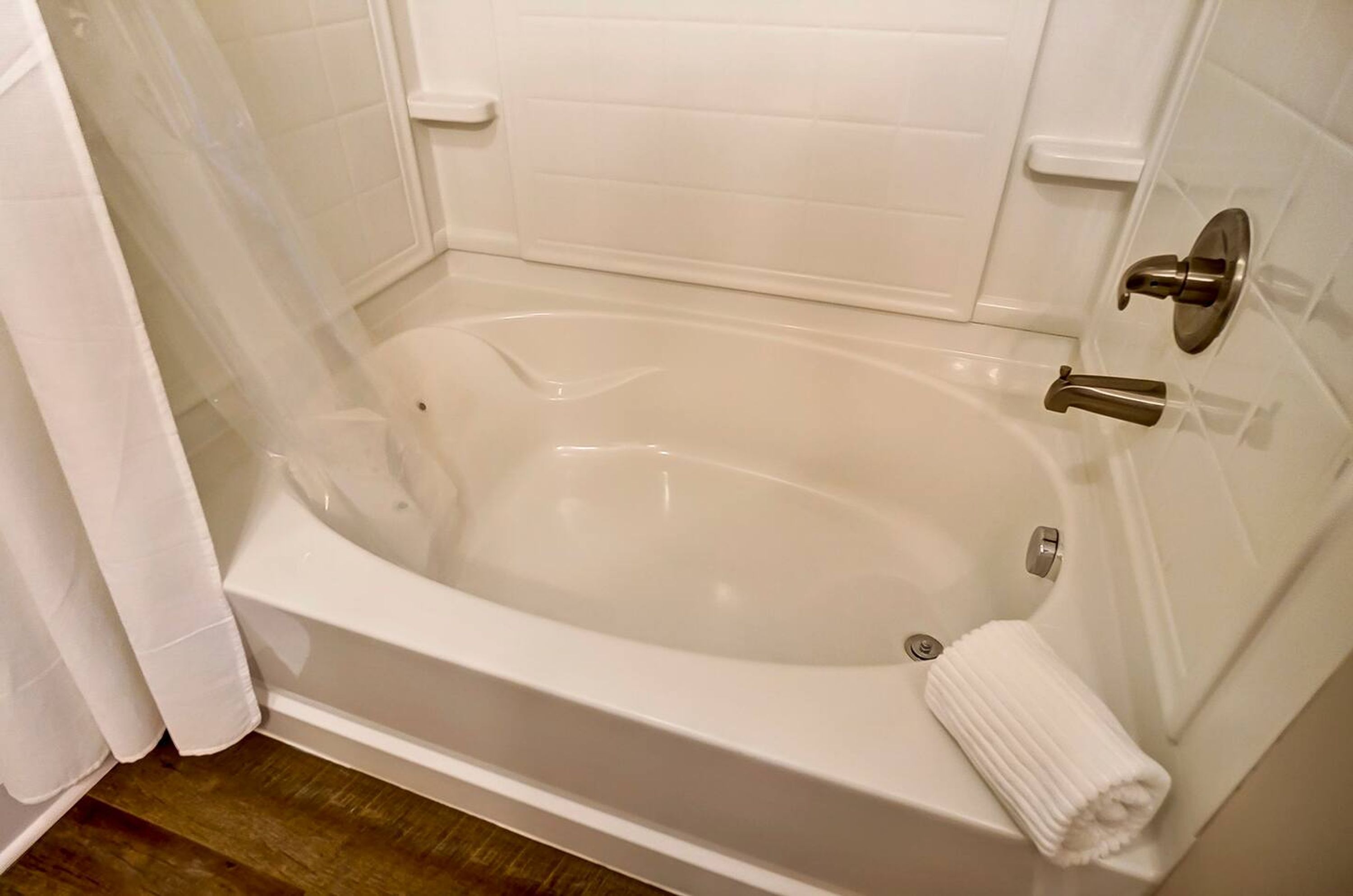 A white bathtub with a shower curtain, a towel, and a wall-mounted faucet.