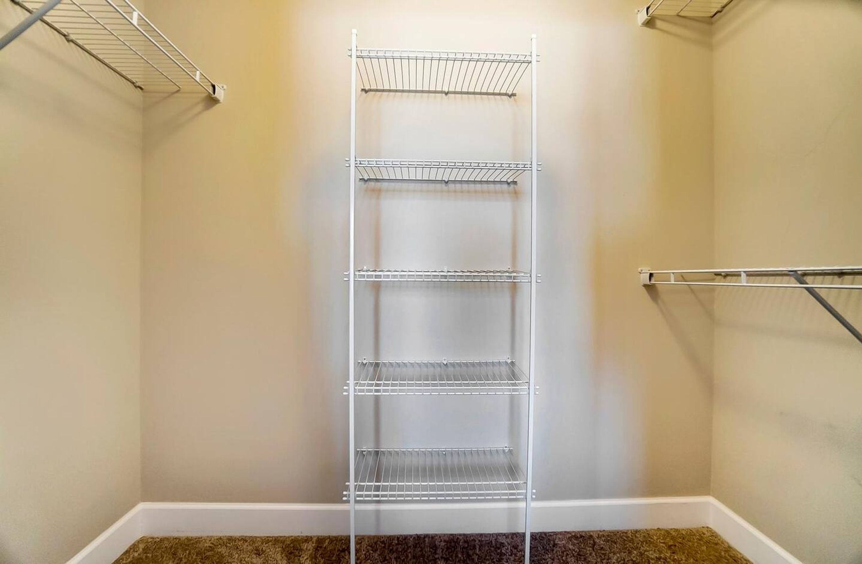 Un vestidor con estanterías metálicas y un perchero.