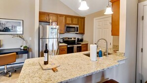 A modern kitchen with granite countertops, stainless steel appliances, wooden cabinets, and pendant lighting. - King Bed Top Floor Washer Dryer Balcony Wifi (Westerville)
