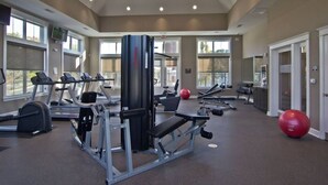 Un gimnasio con cintas de correr, máquinas de pesas y pelotas de ejercicio.