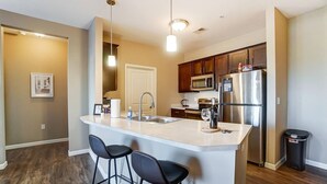 A modern kitchen with a central island, stainless steel appliances, and black bar stools. - Lux Dublin 2BR 1st Floor W D Pet Friendly (Dublin)