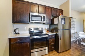 A modern kitchen with dark wood cabinets, stainless steel appliances, and a white countertop. - Lux Dublin 2BR 1st Floor W D Pet Friendly (Dublin)