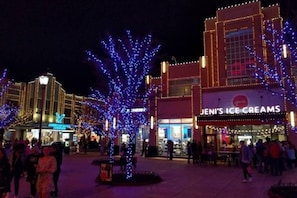 Een winkelgebied met verlichte bomen en een winkel genaamd 'Jeni's Ice Creams'.