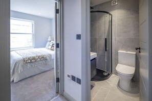 A modern bathroom with a glass shower enclosure, a toilet, and a sink.
