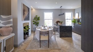 Una cocina moderna con comedor, que cuenta con un piso de madera en espiga, una isla de mármol y un amplio ventanal que proporciona luz natural.