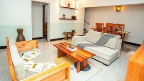 Ein Wohnzimmer mit einer Couch, einem Holztisch und einem Essbereich mit Stühlen.