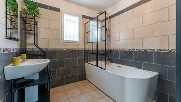 Une salle de bain avec un lavabo blanc, une baignoire et une douche à parois de verre.