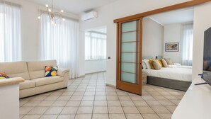 A modern hotel room with a sofa, a bed, a desk, and a sliding door. - Olympic Vatican Home (Roma)