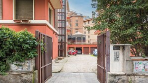 A gated entrance to a residential building with a paved driveway and a parked scooter. - Olympic Vatican Home (Roma)
