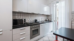 A modern kitchen with white cabinets, a black countertop, a microwave, a stove, and an oven. - Olympic Vatican Home (Roma)