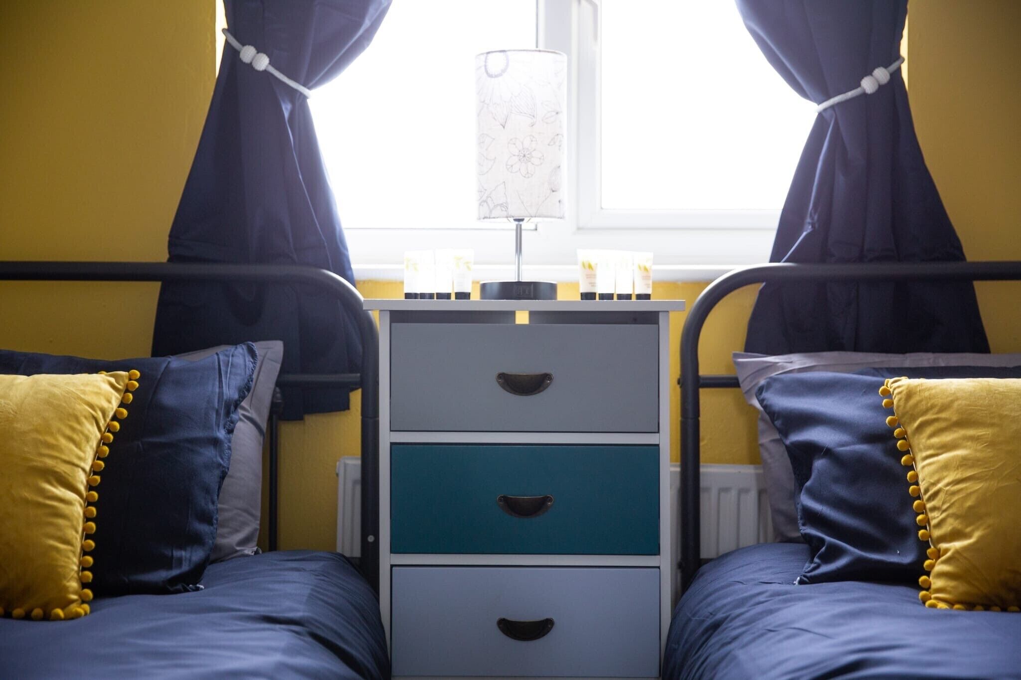 A twin bed with a nightstand, a lamp, and two bedside tables with drawers.