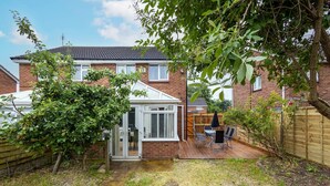 A residential property with a patio area, a wooden deck, and a garden.