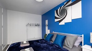 A modern bedroom with a bed, a bedside table, and a wall-mounted towel rack.