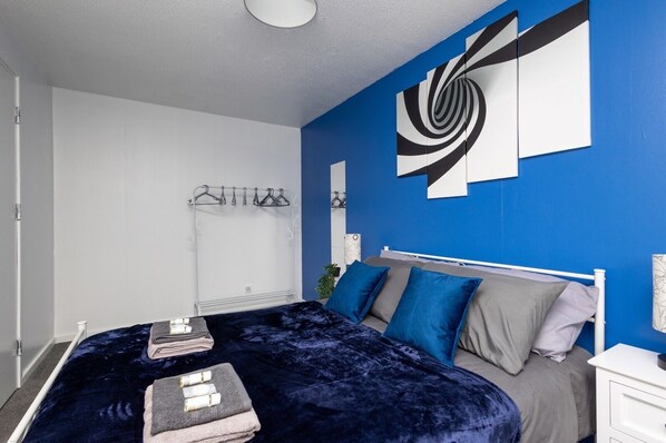 Un dormitorio moderno con cama, una mesita de noche y un perchero en la pared.